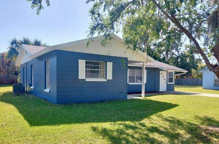 A blue, single-story house with white trim and shutters sits on a grassy lawn — 2315 QUEEN PALM DRIVE, EDGEWATER, FL