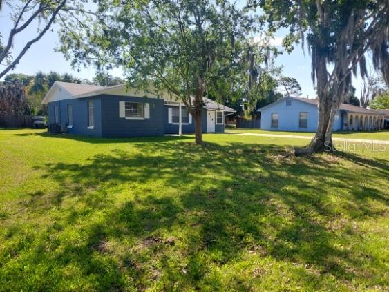 A blue single-story house with a large grassy yard and a neighboring house nearby — 2315 QUEEN PALM DRIVE, EDGEWATER, FL