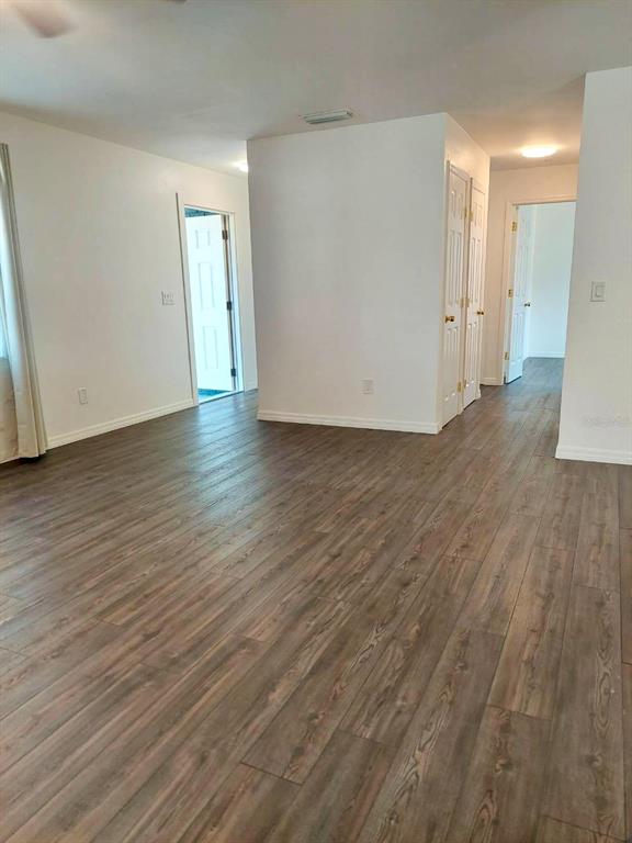 An empty room features wood-look flooring, white walls, and multiple doorways leading to other areas — 2315 QUEEN PALM DRIVE, EDGEWATER, FL