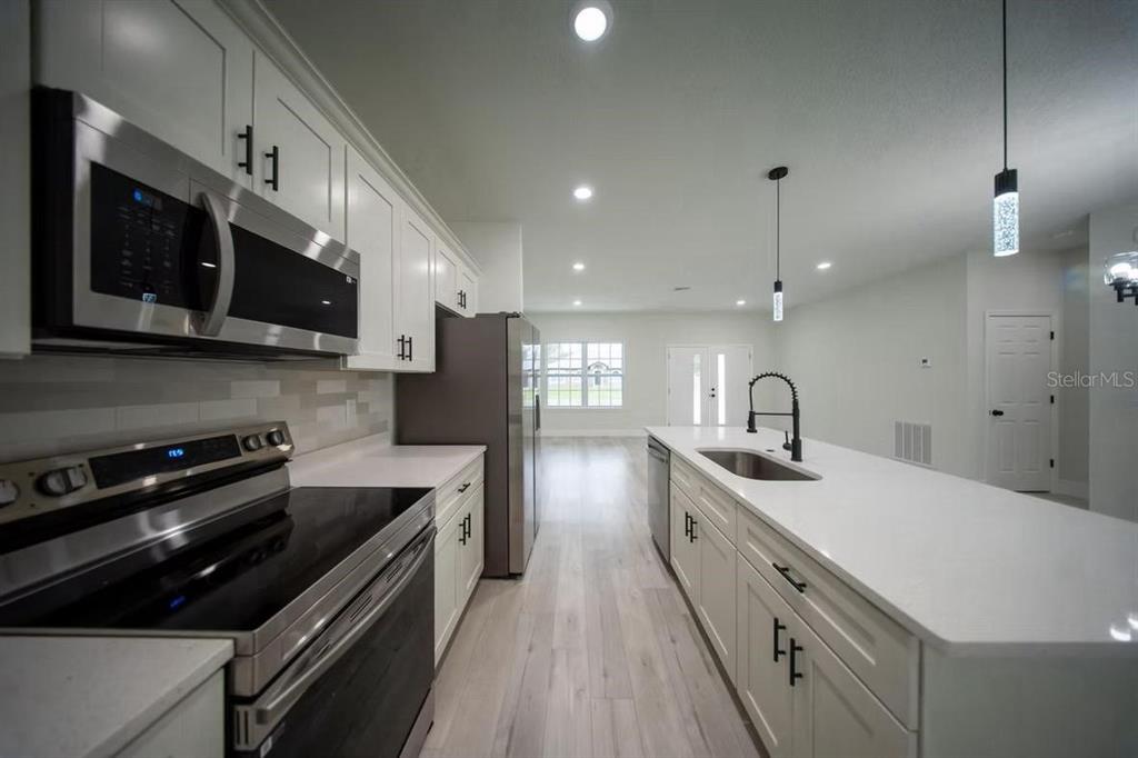 A modern kitchen features white cabinetry, stainless steel appliances, and a large central island — 3286 W CRANDON DRIVE, CITRUS SPRINGS, FL