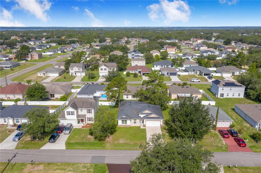 An aerial view shows a suburban neighborhood with single-family homes, paved streets, and green lawns — 1608 PILCHARD COURT, POINCIANA, FL