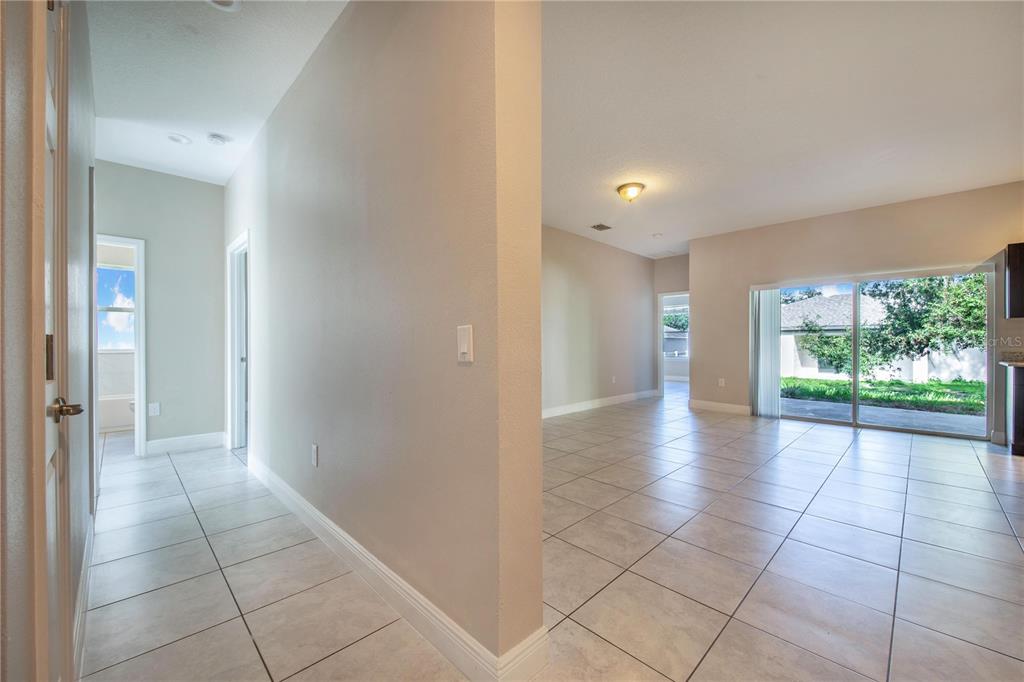 A tiled hallway leads to an open living area with sliding glass doors to the backyard — 1608 PILCHARD COURT, POINCIANA, FL