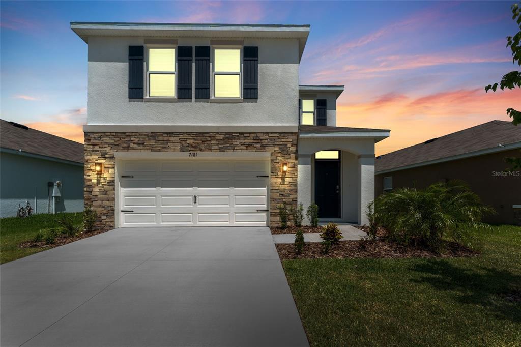 A two-story house with a stone-accented facade, a two-car garage, and a concrete driveway — 7181 BROAD RIVER AVENUE, LAND O LAKES, FL