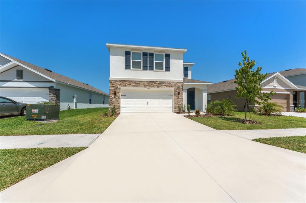 A two-story house with a stone facade, white stucco, and a two-car garage — 7181 BROAD RIVER AVENUE, LAND O LAKES, FL