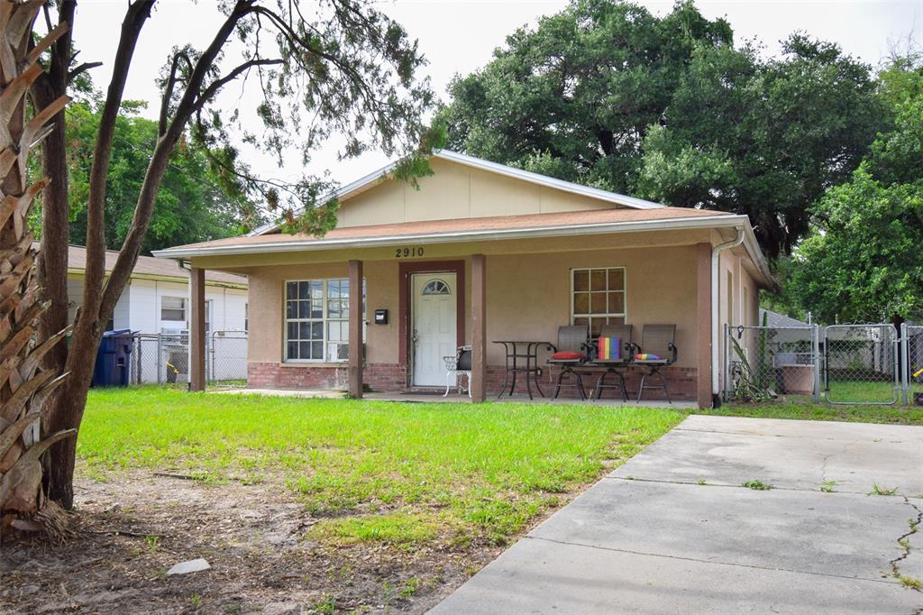 A single-story house with a covered front porch, tan stucco siding, and a concrete driveway — 2910 E 25TH AVENUE, TAMPA, FL