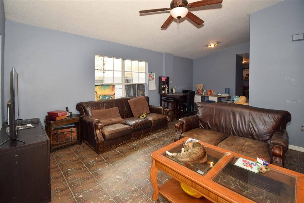 A living room features two brown leather sofas, a glass-topped coffee table, and tiled flooring — 2910 E 25TH AVENUE, TAMPA, FL
