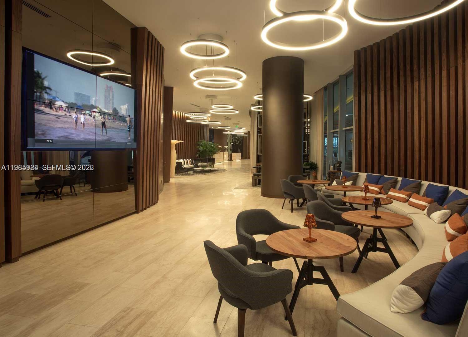 A modern lounge area features circular pendant lights, wood-slatted walls, and curved bench seating — 4111 S Ocean Dr # 1210, Hollywood FL 33019, HOLLYWOOD, FL