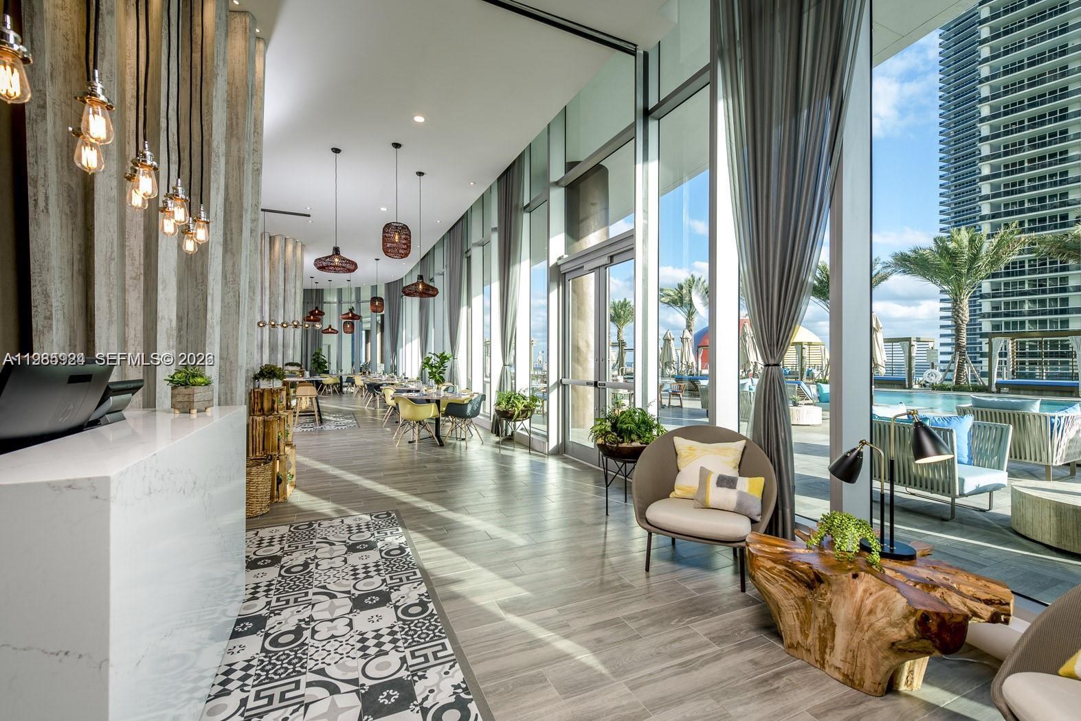 A modern lobby features a patterned tile floor, floor-to-ceiling windows, and an outdoor pool area — 4111 S Ocean Dr # 1210, Hollywood FL 33019, HOLLYWOOD, FL