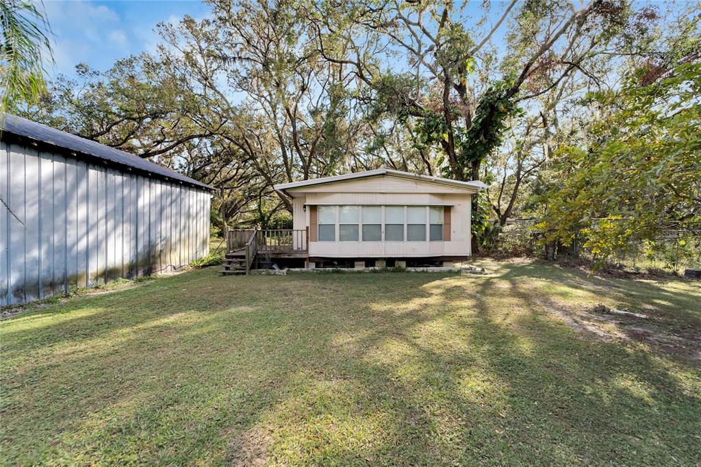 A mobile home with a screened-in porch sits on a grassy lot near a shed — 5030 SYDNEY ROAD, PLANT CITY, FL