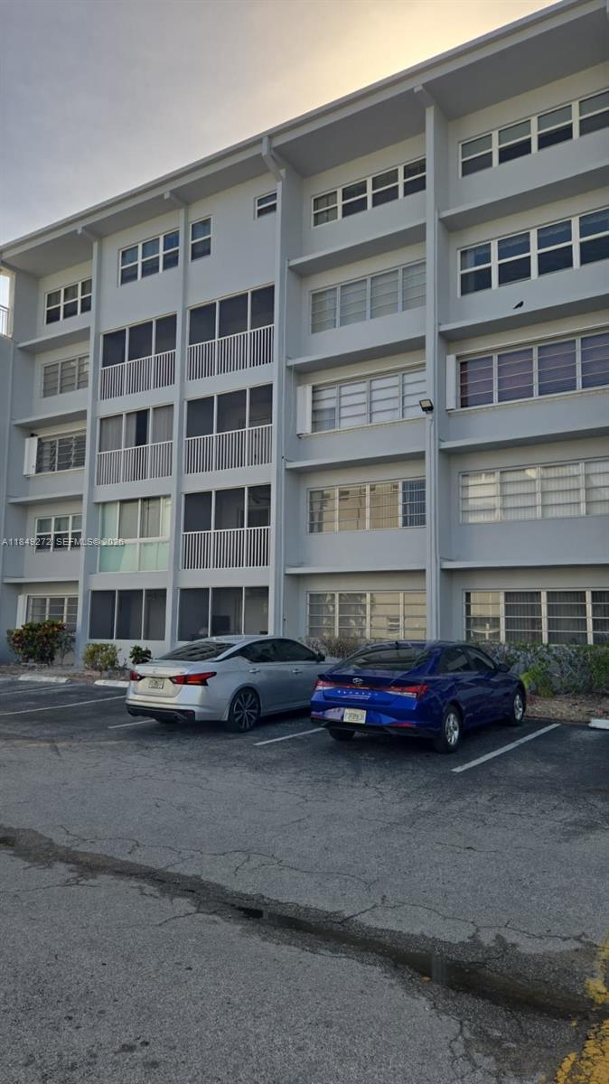 A multi-story apartment building exterior features screened balconies and a parking lot with two cars — 215 SE 3rd Ave # 403A, Hallandale Beach FL 33009, HALLANDALE BEACH, FL