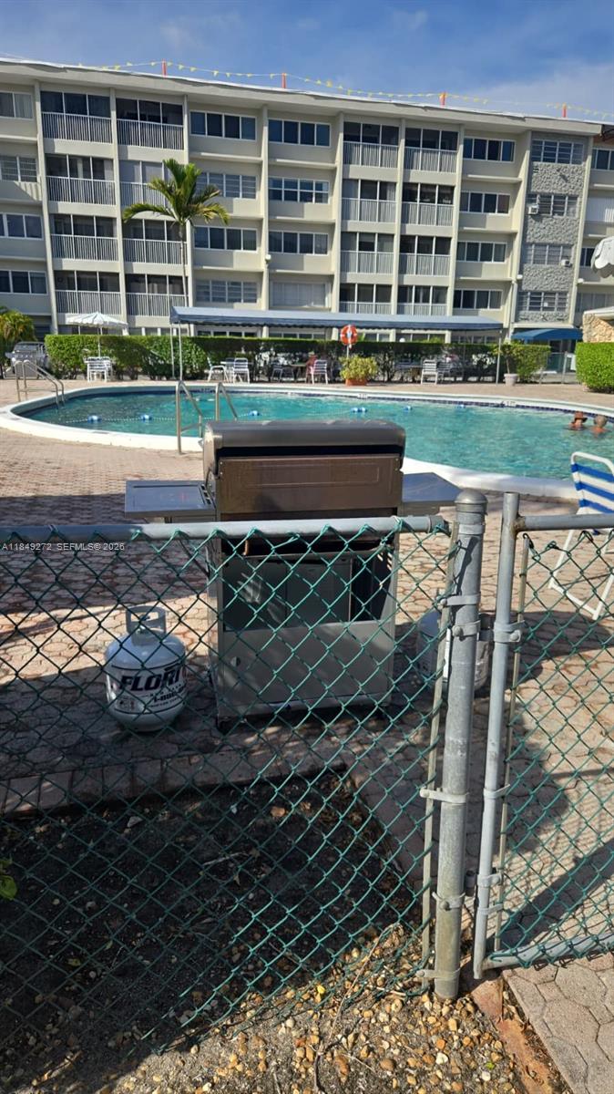 A stainless steel grill sits on a patio next to a swimming pool and building — 215 SE 3rd Ave # 403A, Hallandale Beach FL 33009, HALLANDALE BEACH, FL