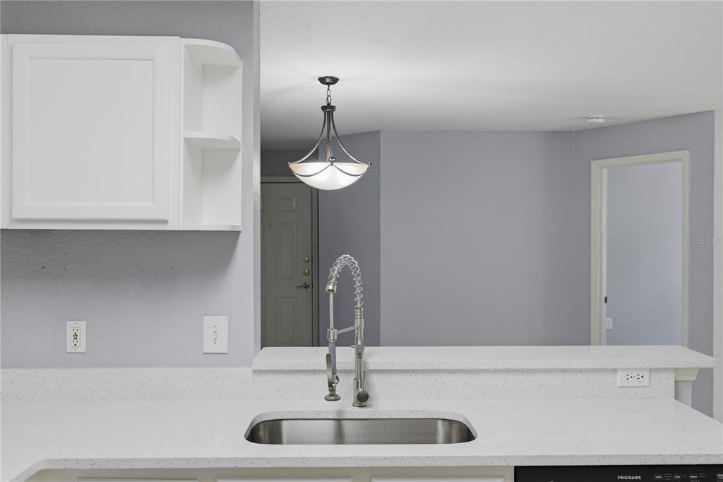 A kitchen sink with a gooseneck faucet sits in a white countertop with white cabinets — 7605 PISSARRO DRIVE UNIT 13204, ORLANDO, FL