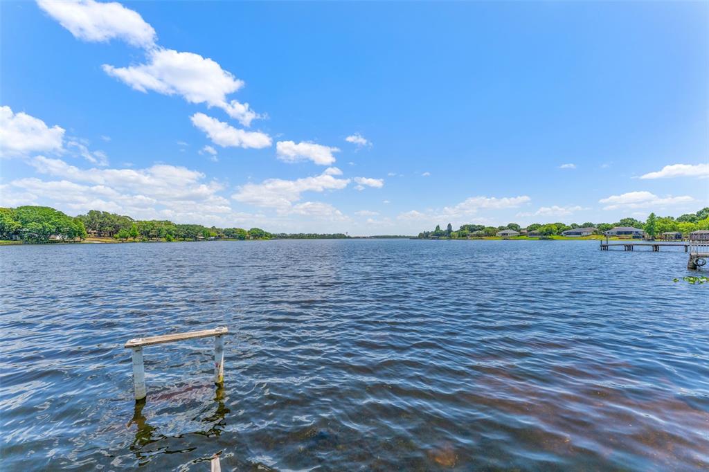A view of a lake with a wooden post in the foreground and a dock — 7558 BERKLEY ROAD, POLK CITY, FL