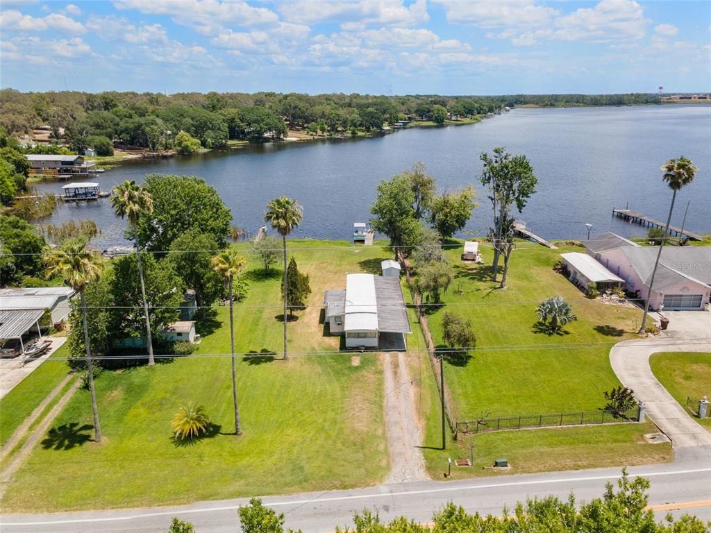 An aerial view shows a mobile home on a large grassy lot facing a lake — 7558 BERKLEY ROAD, POLK CITY, FL