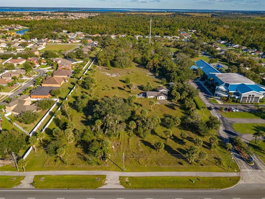 An aerial view shows a large, grassy vacant lot with scattered trees and a small house — 4051 PLEASANT HILL ROAD, KISSIMMEE, FL