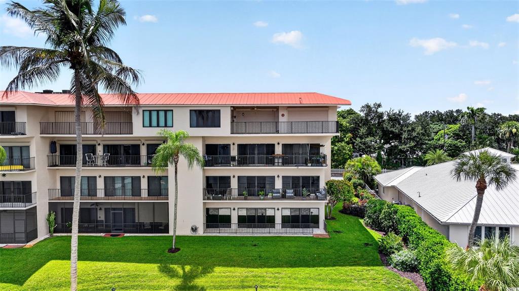 A multi-story apartment building with balconies overlooks a green lawn and palm trees — 624 SW ST LUCIE CRESCENT UNIT UN208, STUART, FL