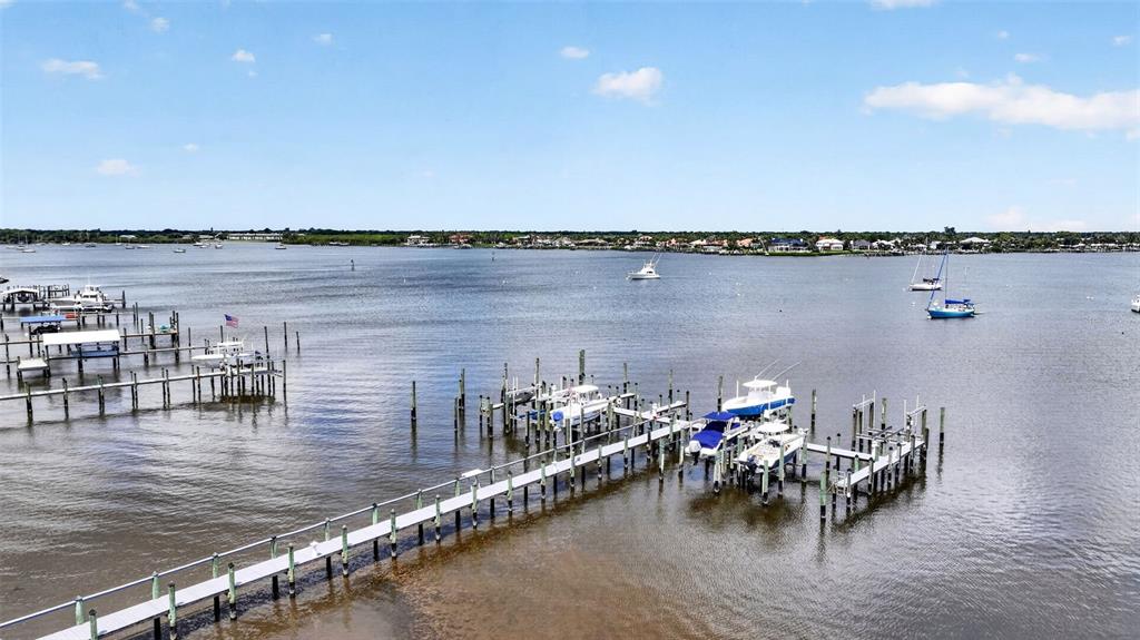 An aerial view of a wooden dock extending into a bay with several moored boats — 624 SW ST LUCIE CRESCENT UNIT UN208, STUART, FL