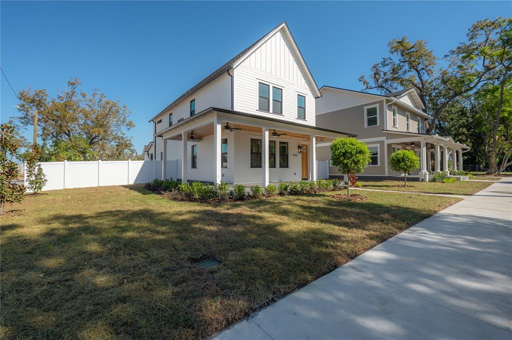 A white two-story house with a covered front porch sits next to a tan house — 802 E WILDER AVENUE, TAMPA, FL