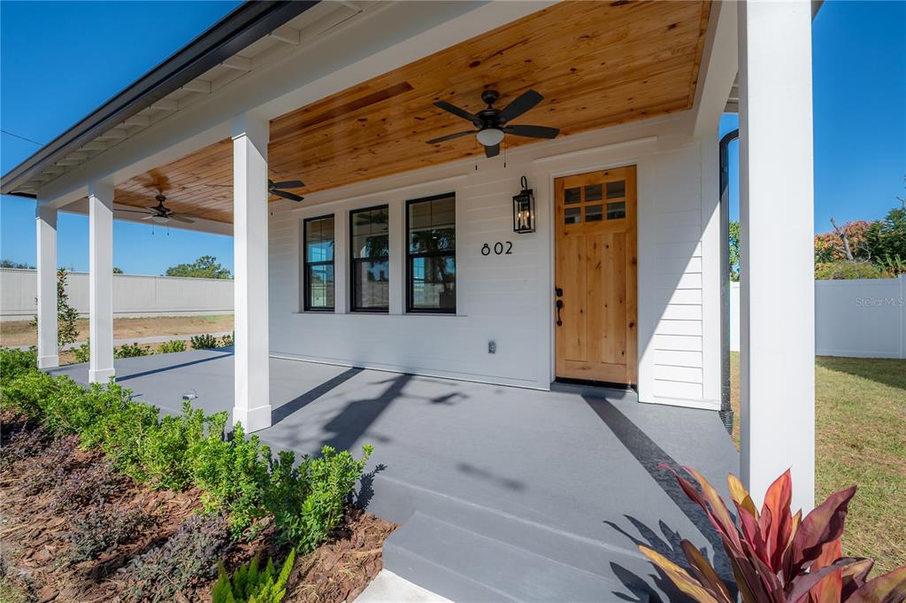 A covered front porch features a wood-paneled ceiling, ceiling fans, and a wooden front door — 802 E WILDER AVENUE, TAMPA, FL