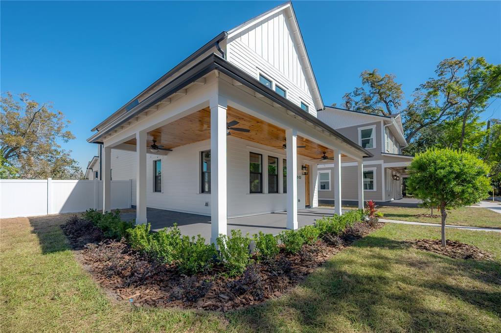 A white house with a large covered porch featuring a wood-paneled ceiling and ceiling fans — 802 E WILDER AVENUE, TAMPA, FL