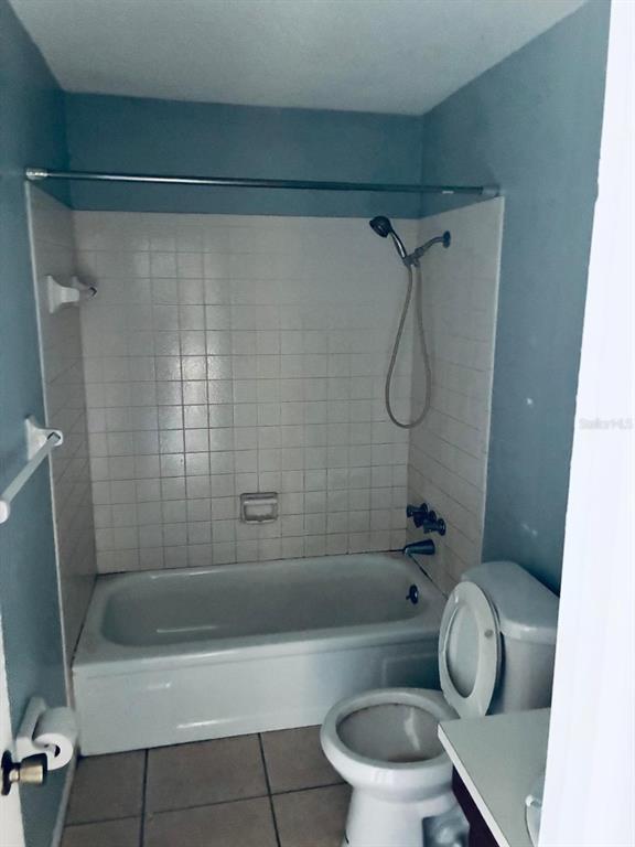 A bathroom features a white bathtub with a showerhead, a toilet, and light blue walls — 6031 CRAFTON DRIVE, LAKELAND, FL