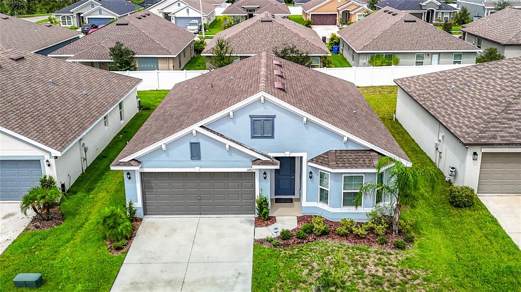 An aerial view of a light blue single-story house with a brown shingled roof — 14917 TROPICAL VIOLET WAY, WIMAUMA, FL