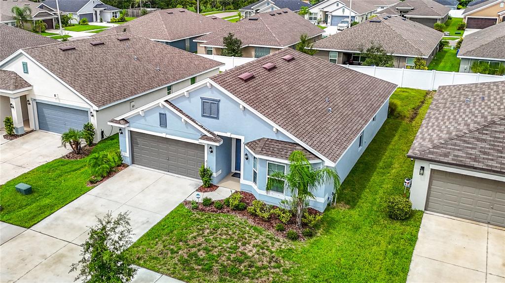 An aerial view of a light blue suburban house with a brown shingled roof — 14917 TROPICAL VIOLET WAY, WIMAUMA, FL