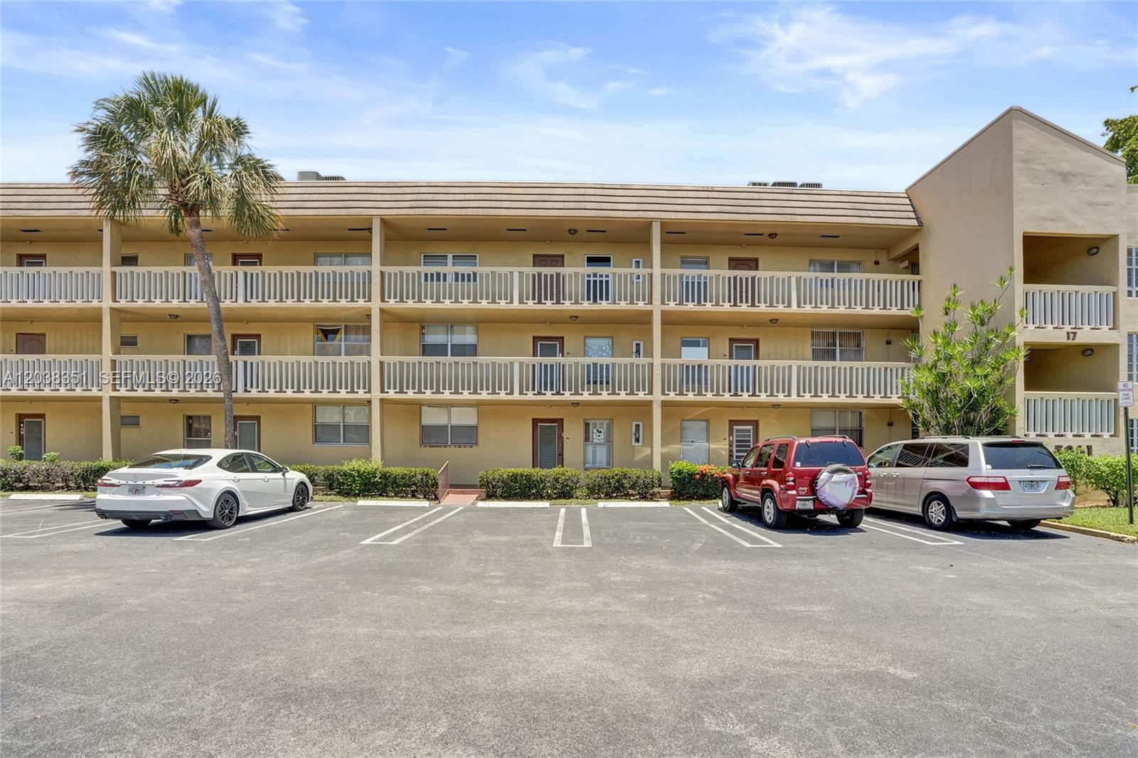 A three-story apartment building with a parking lot and palm tree in front — 5961 NW 61st Ave # 310, Tamarac FL 33319, TAMARAC, FL
