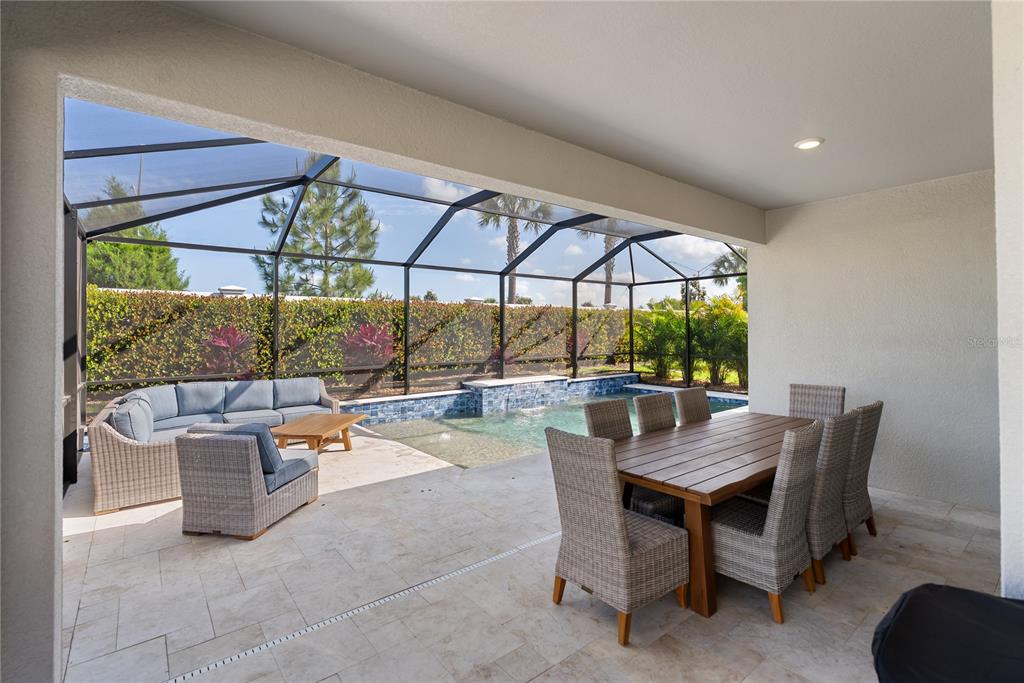 A modern kitchen features white cabinets, a marble-topped island with a sink, and stainless appliances — 17526 SAVORY MIST CIRCLE, BRADENTON, FL