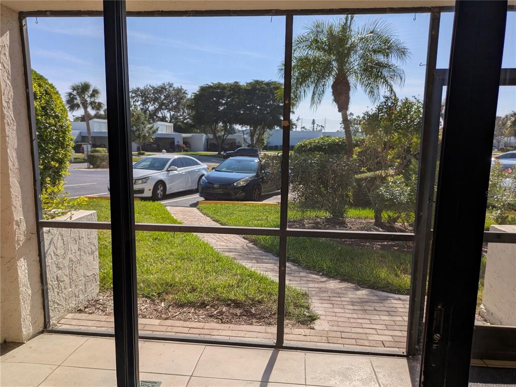 A view from a screened-in porch looking out onto a parking lot and palm trees — 6114 43RD STREET W UNIT 106E, BRADENTON, FL