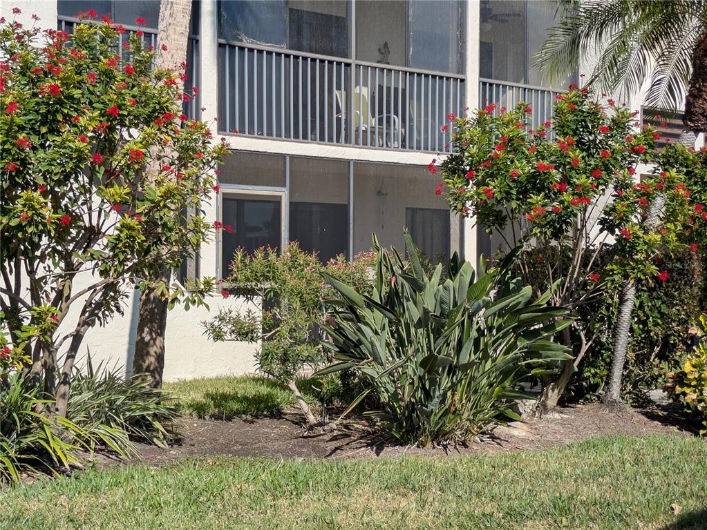 A ground-floor patio with a screened enclosure sits beneath a balcony with a metal railing — 6114 43RD STREET W UNIT 106E, BRADENTON, FL