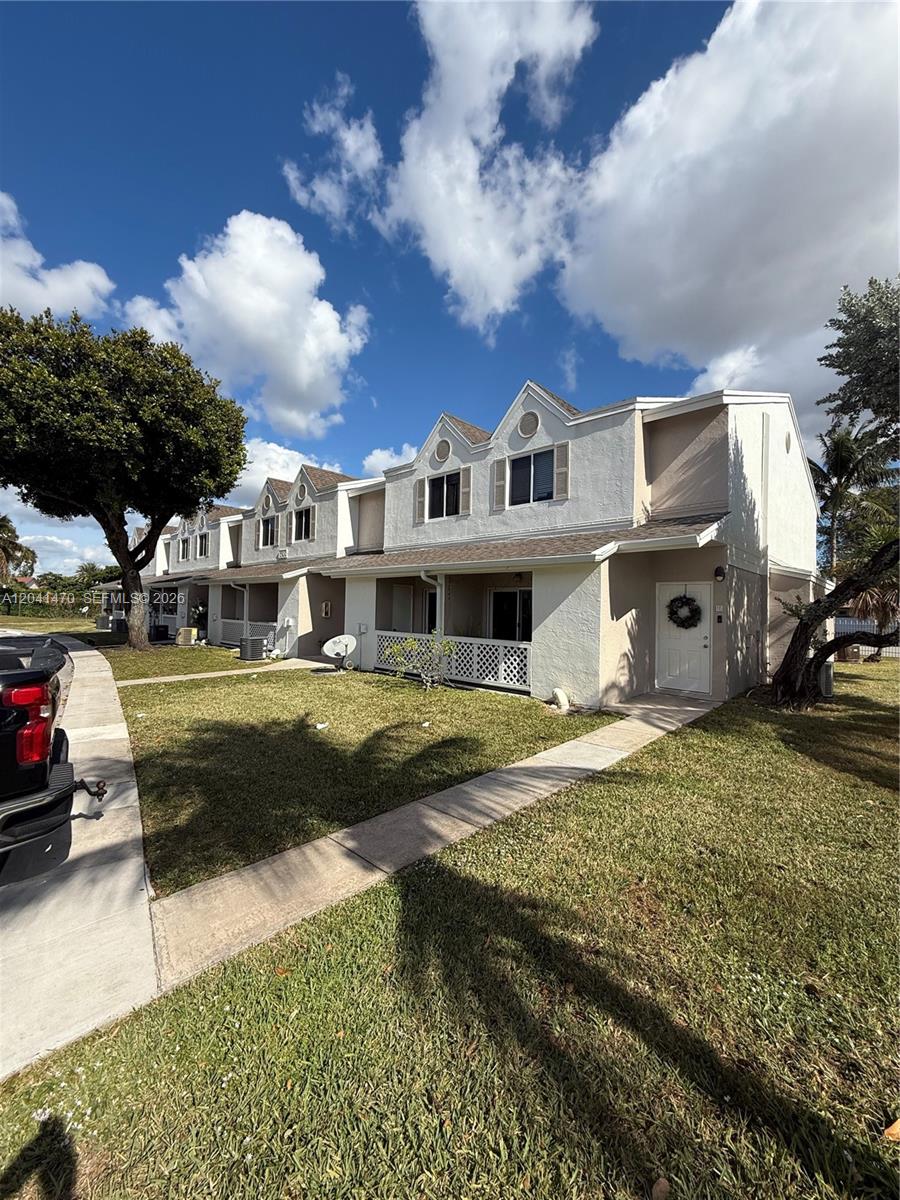 A two-story townhouse exterior with a white facade, gabled rooflines, and a front lawn — 17515 NW 67th Ct # 22, Hialeah FL 33015, HIALEAH, FL