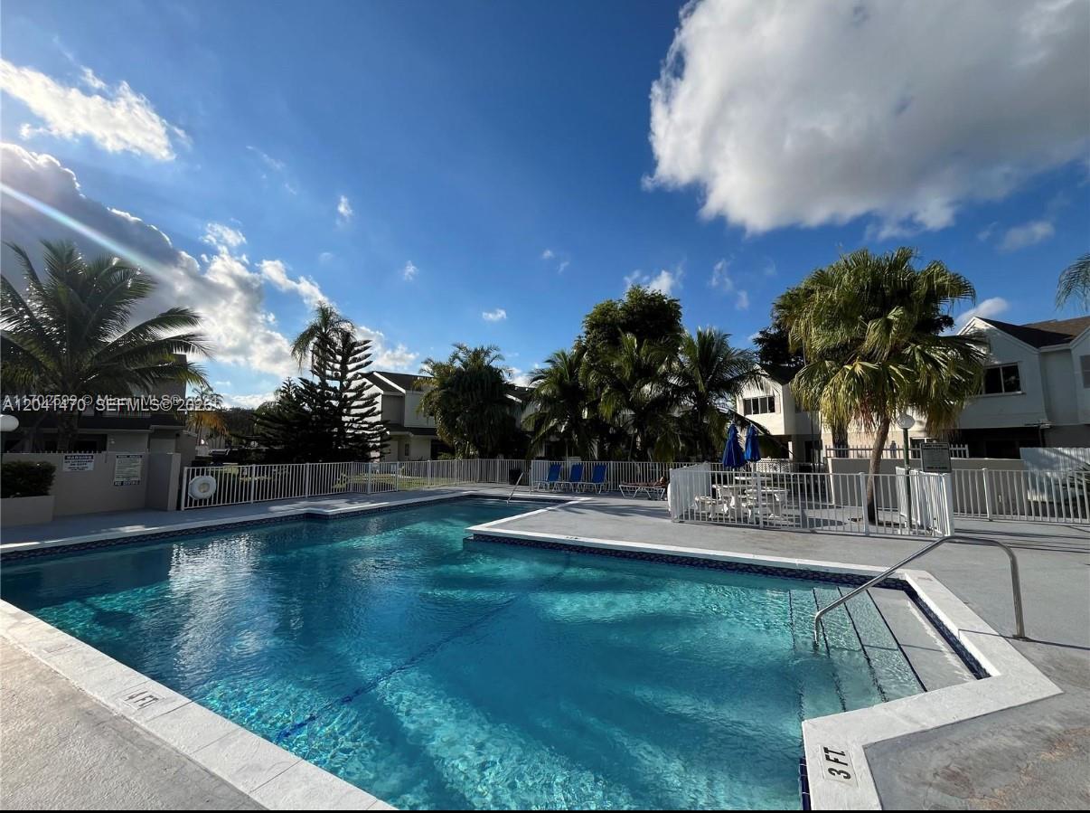 A swimming pool with a shallow end and surrounding palm trees under a blue sky — 17515 NW 67th Ct # 22, Hialeah FL 33015, HIALEAH, FL