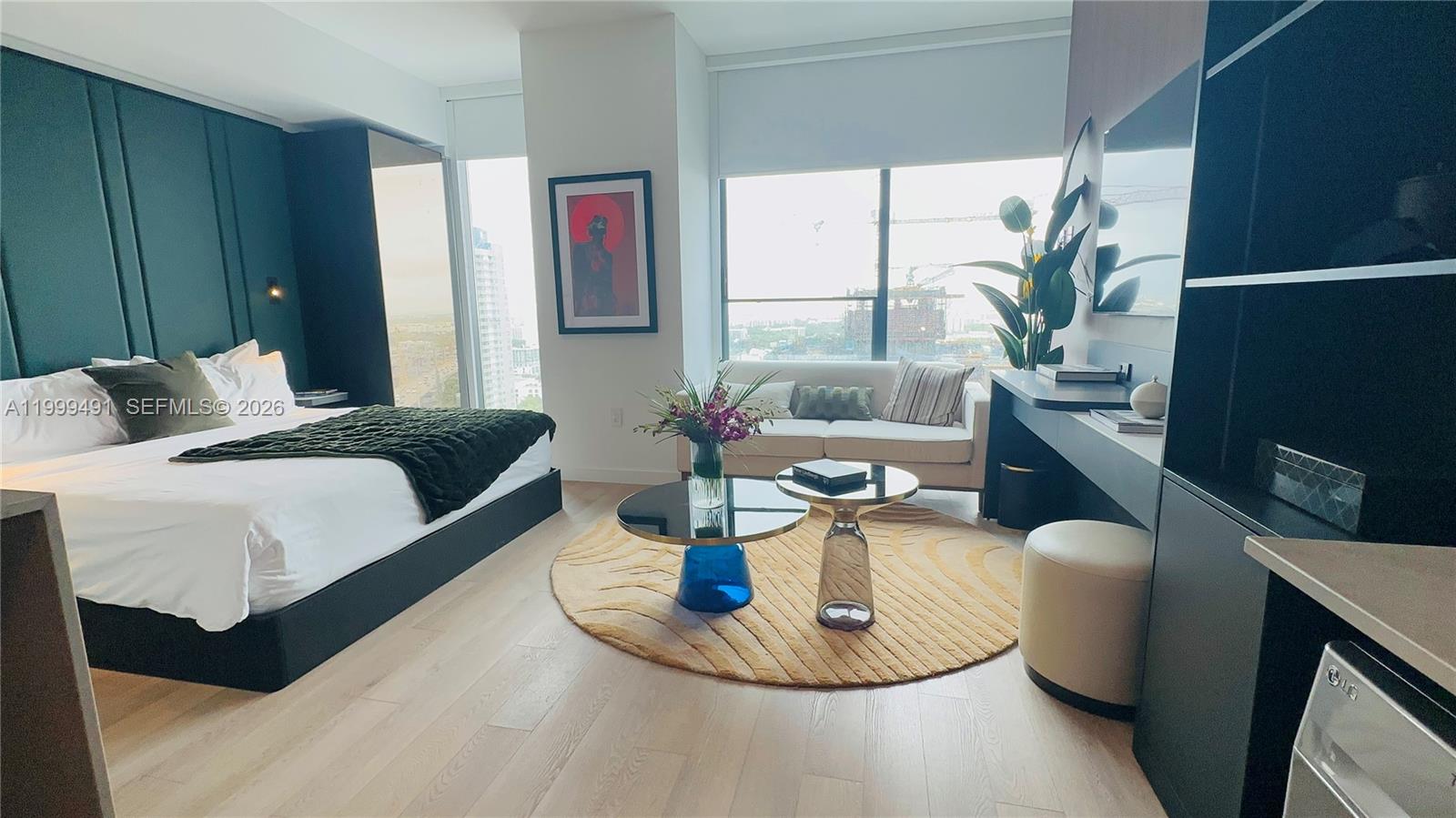 A modern bedroom features a bed, a small seating area, and a view of construction — 20 NE 11 St, Miami FL 33132, MIAMI, FL