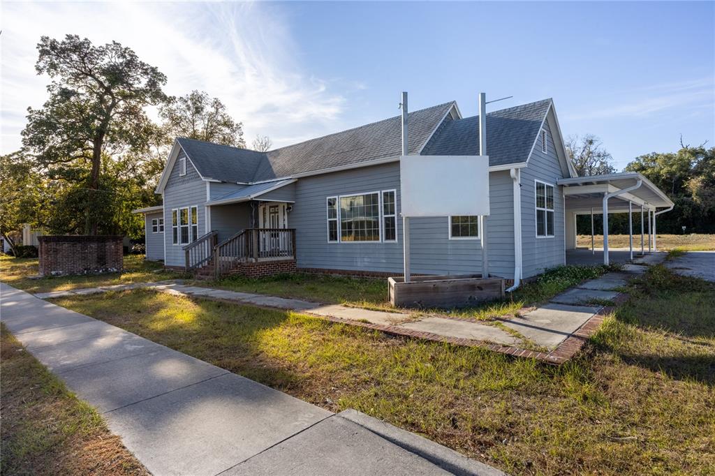 A gray, single-story building with a front porch, a carport, and a blank sign — 18420 HIGH SPRINGS MAIN STREET, HIGH SPRINGS, FL