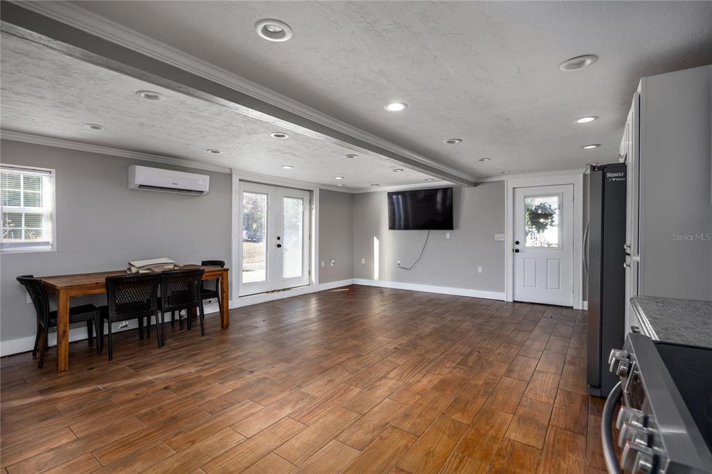 A living and dining area features wood-look tile flooring, recessed lighting, and a wall-mounted television — 18420 HIGH SPRINGS MAIN STREET, HIGH SPRINGS, FL