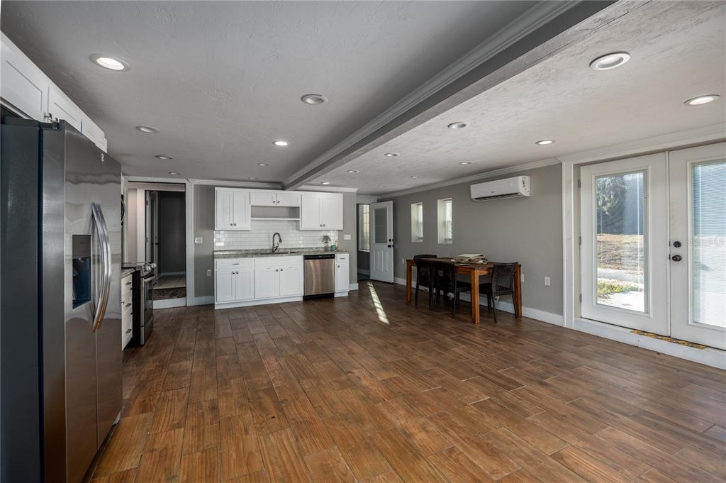 A kitchen and dining area with white cabinets, wood-look tile floors, and glass patio doors — 18420 HIGH SPRINGS MAIN STREET, HIGH SPRINGS, FL