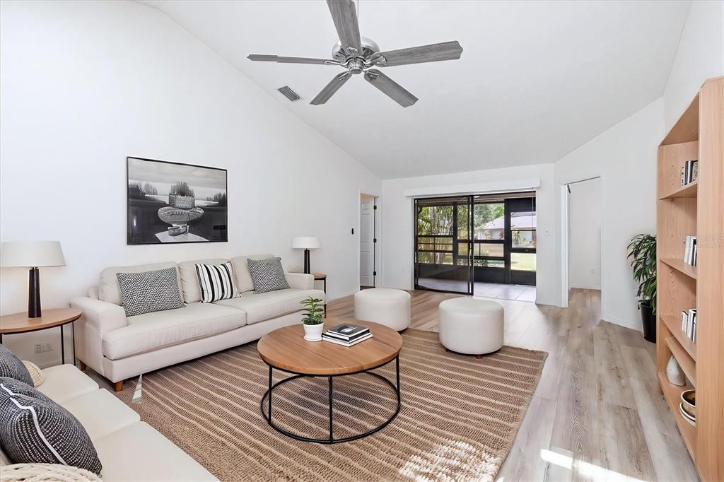A living room with a vaulted ceiling, light wood floors, a sofa, and a coffee table — 4793 OAK FOREST DRIVE W UNIT 46, SARASOTA, FL