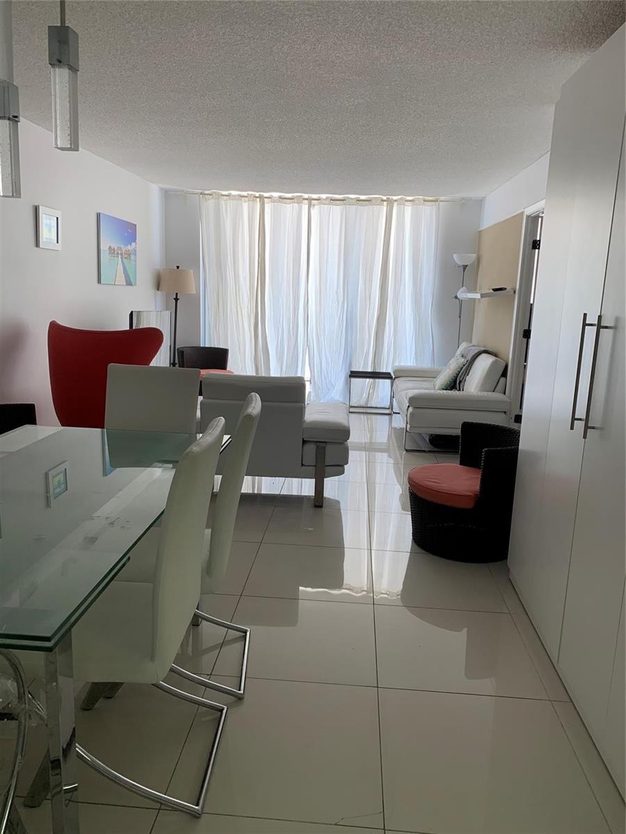 A living and dining area features white tile floors, modern furniture, and floor-to-ceiling curtains — 101 Briny Avenue # 806, Pompano Beach FL 33062, POMPANO BEACH, FL