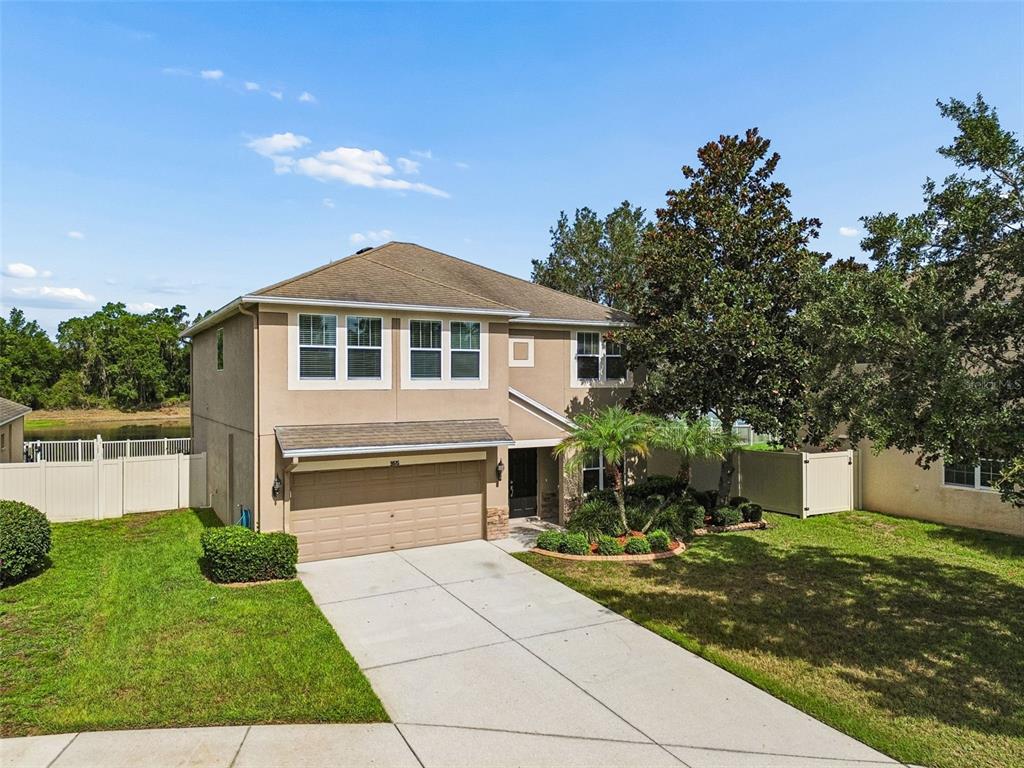 A two-story suburban house with a tan stucco exterior, a two-car garage, and a driveway — 9615 REGIMENT COURT, LAND O LAKES, FL