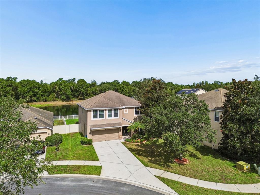 An aerial view of a two-story suburban house with a driveway and a backyard pond — 9615 REGIMENT COURT, LAND O LAKES, FL