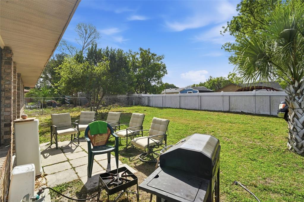 A backyard patio features several chairs, a grill, and a white privacy fence — 783 S ATMORE CIRCLE, DELTONA, FL