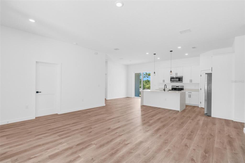 An open-concept kitchen and living area features white cabinetry, a central island, and wood-look flooring — 8812 N LANSEN WAY, CITRUS SPRINGS, FL