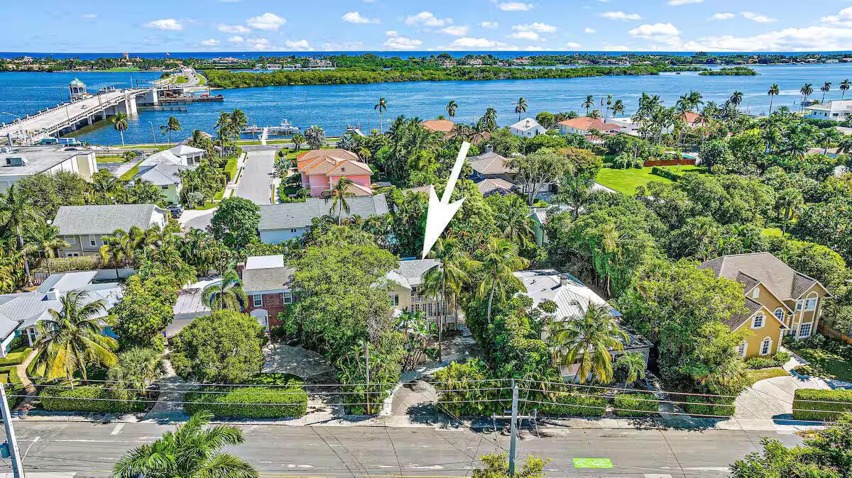 An aerial view shows a house surrounded by lush trees near a bridge and water — 4110 Washington Road, West Palm Beach FL 33405, WEST PALM BEACH, FL