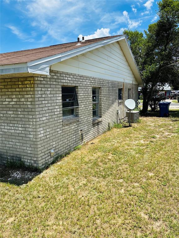 The exterior of a single-story house features light-colored brick walls, white siding, and a satellite dish — 845 S CHAR MIL AVENUE, LAKE ALFRED, FL