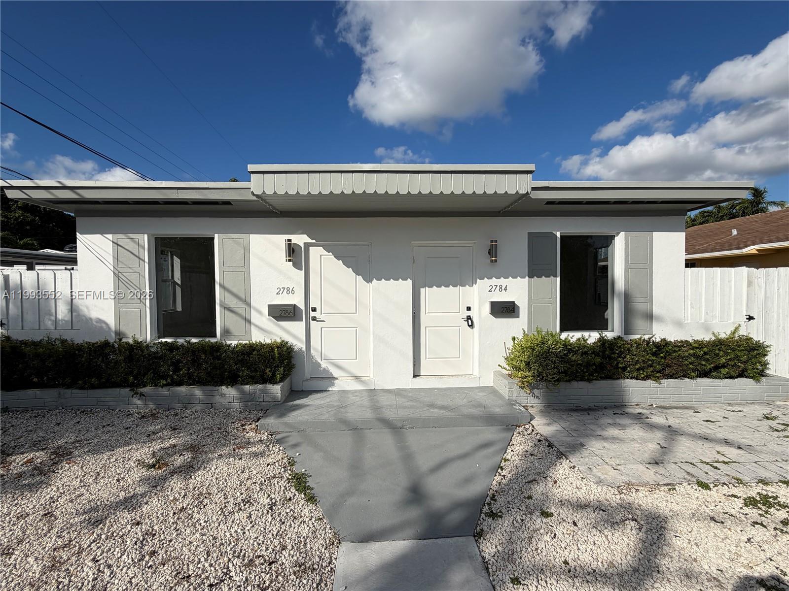 A duplex exterior features white walls, two front doors, and a gravel front yard — 2784 SW 31st Pl, Miami FL 33133, MIAMI, FL