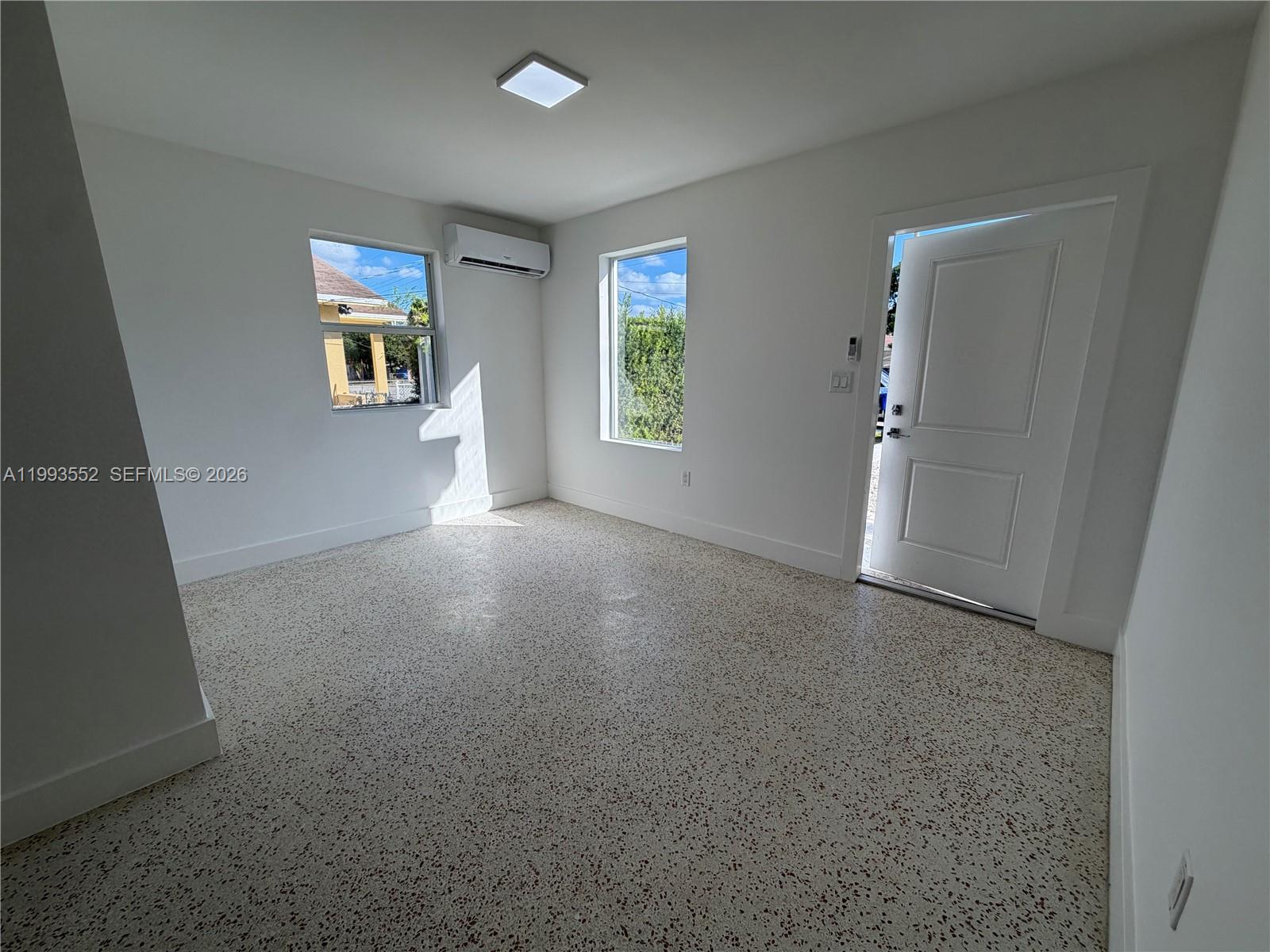 A bright, empty room features white walls, a terrazzo floor, two windows, and a door — 2784 SW 31st Pl, Miami FL 33133, MIAMI, FL