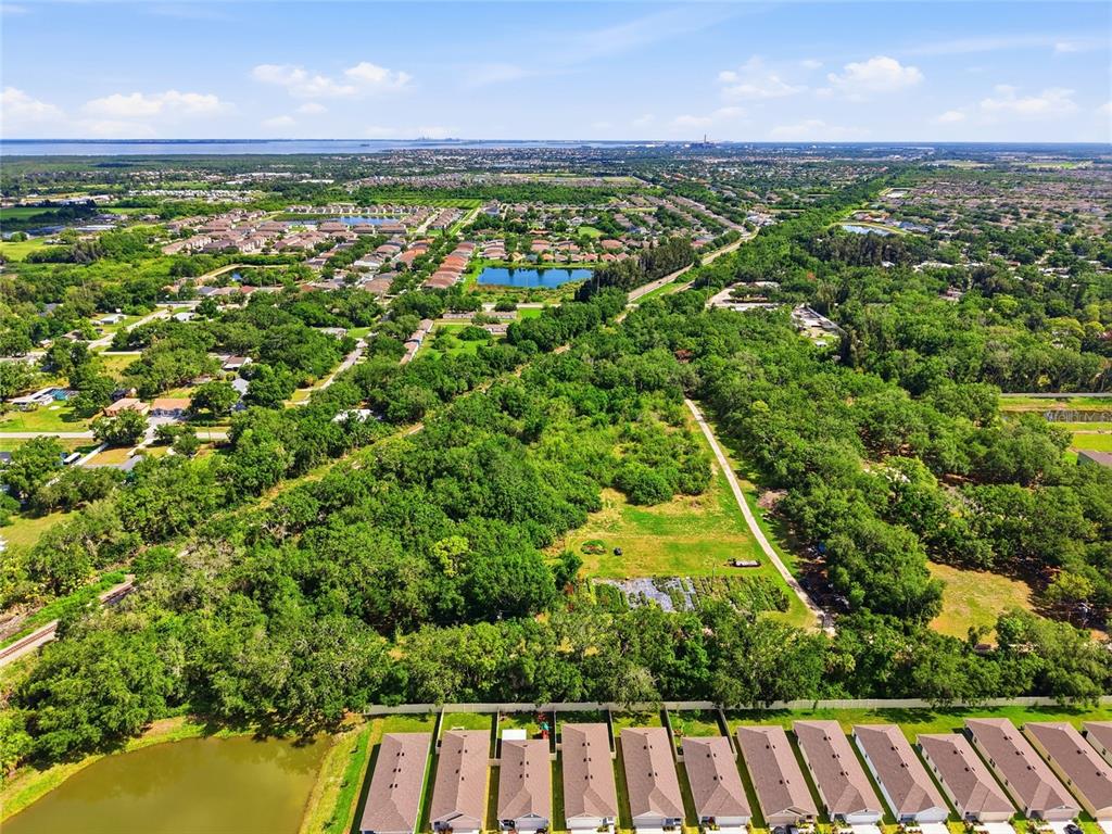An aerial view shows a residential neighborhood bordering a large, wooded undeveloped lot — 910 1010 & 1016  3RD AVE SE AVENUE SE, RUSKIN, FL