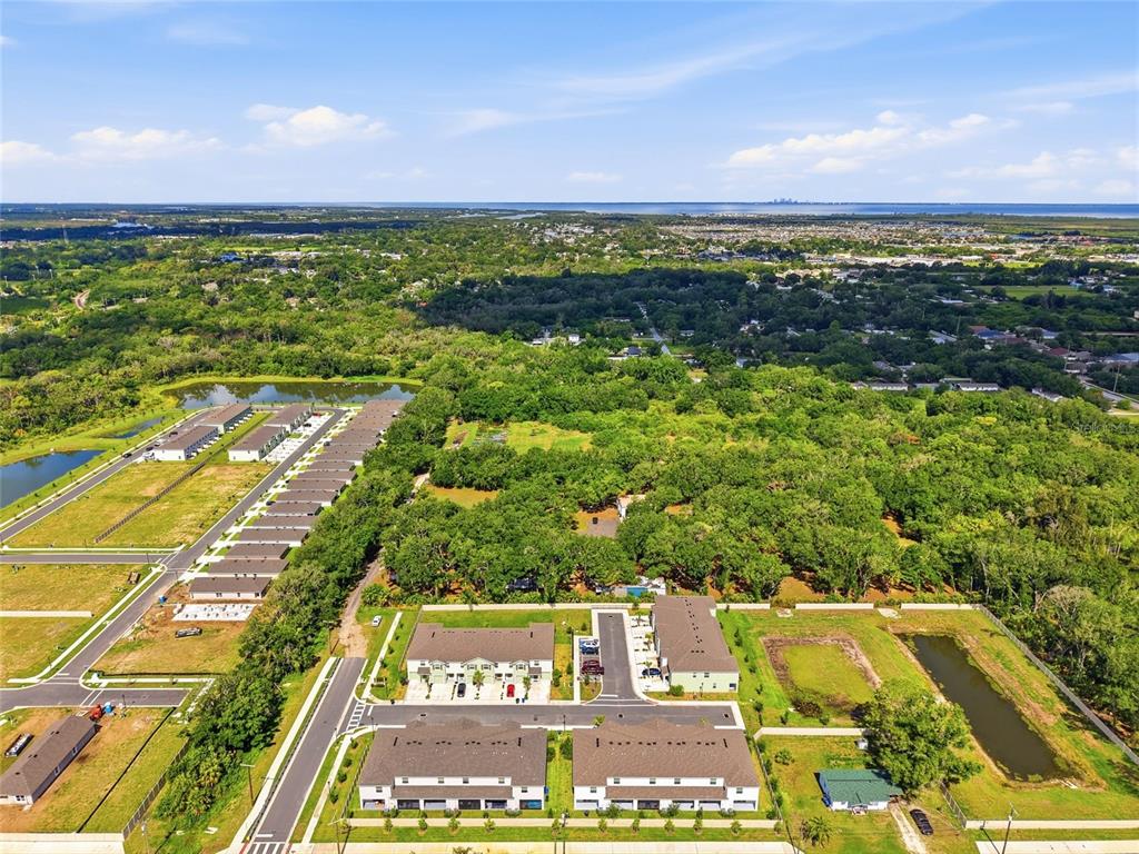 An aerial view shows a residential development with townhomes, green space, and a distant coastline — 910 1010 & 1016  3RD AVE SE AVENUE SE, RUSKIN, FL