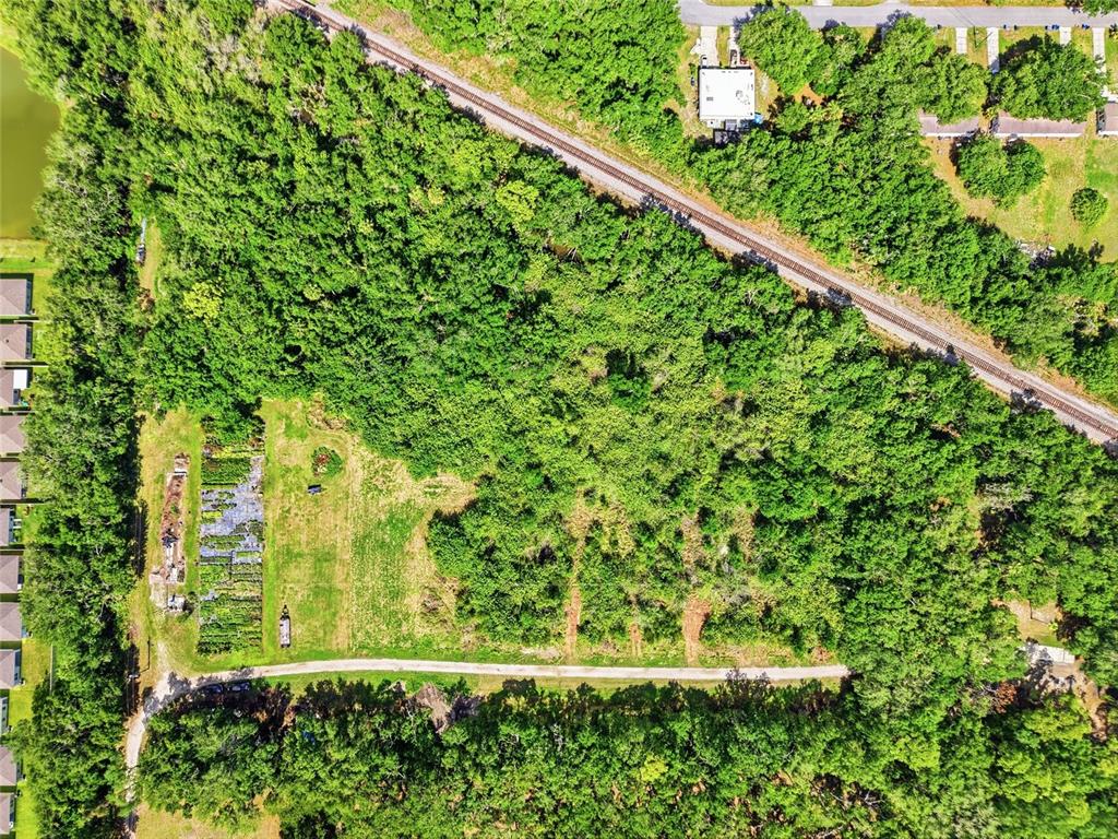 An aerial view shows a wooded lot with a dirt road and railroad tracks nearby — 910 1010 & 1016  3RD AVE SE AVENUE SE, RUSKIN, FL